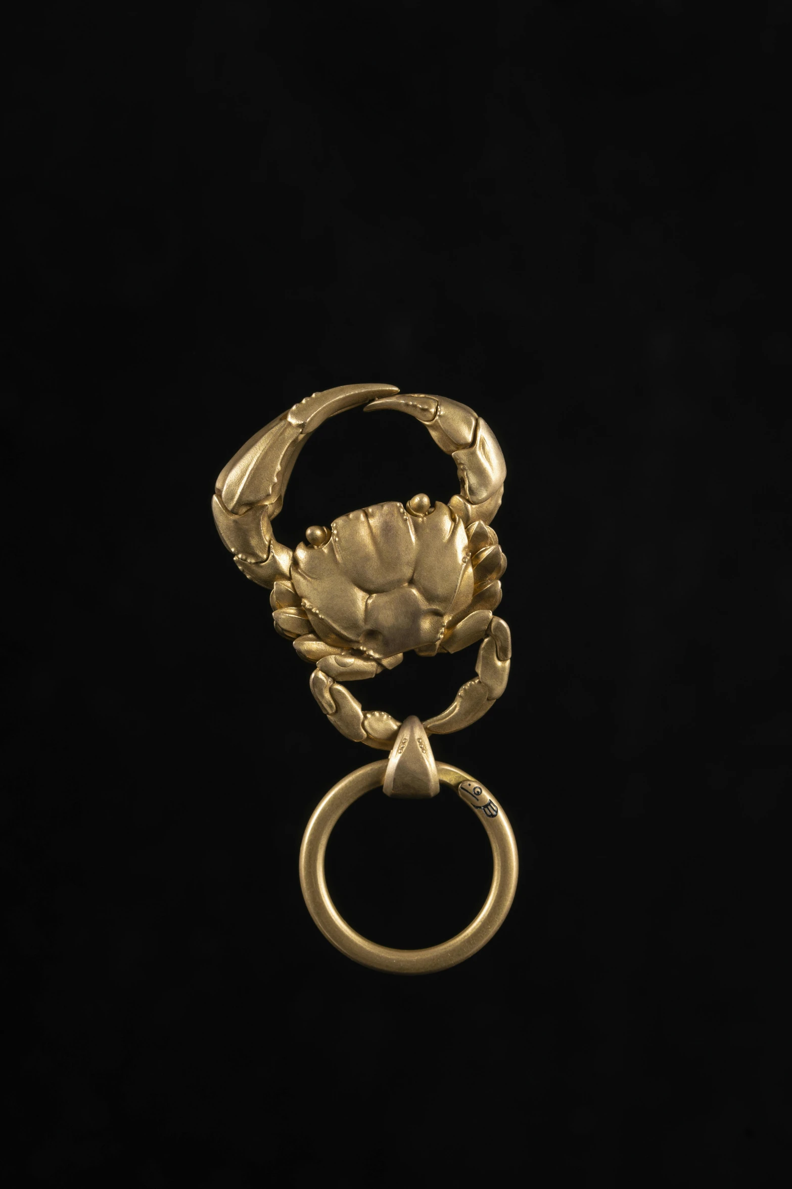 a gold crab ring with an open claw on top of it