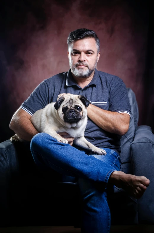 a man sitting in a chair while holding a dog