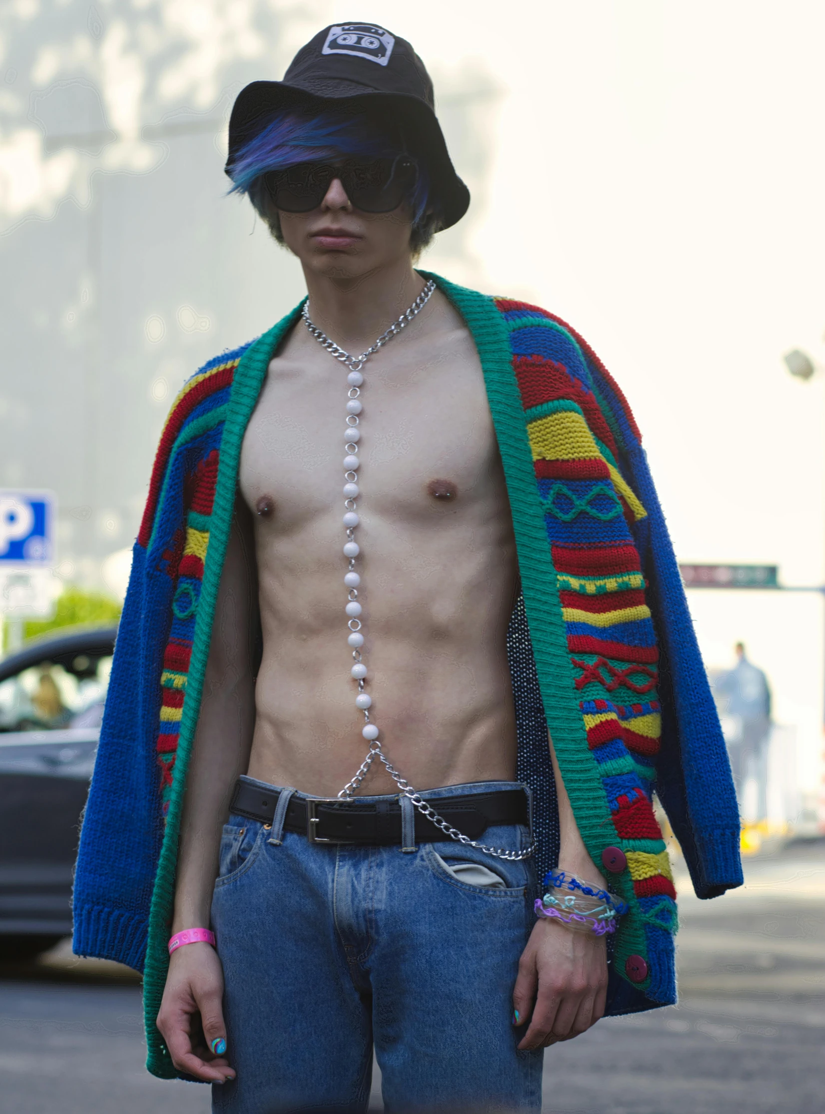 a man wearing a hat, scarf and sunglasses, with a necklace around his neck