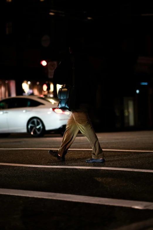 a crosswalk in the dark with a man walking down the street