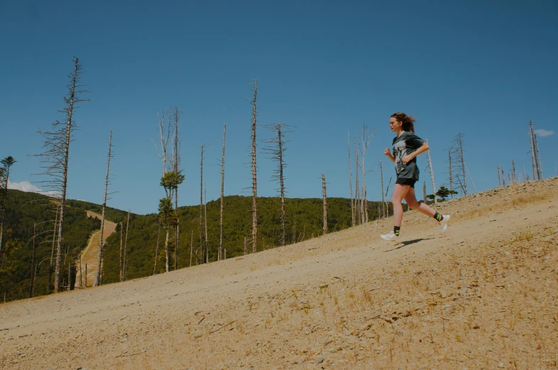 a woman running up a hill in the dirt