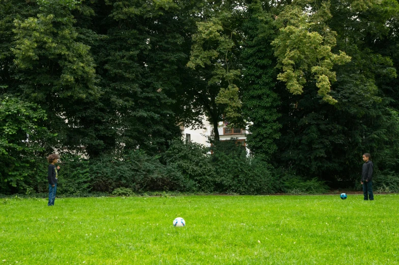 three people play soccer with a ball in the grass