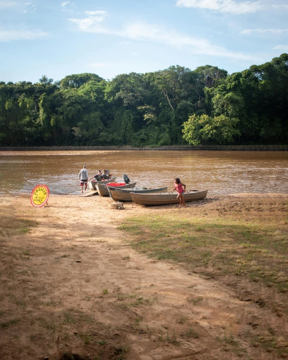 several canoes and people at the edge of a riverbank