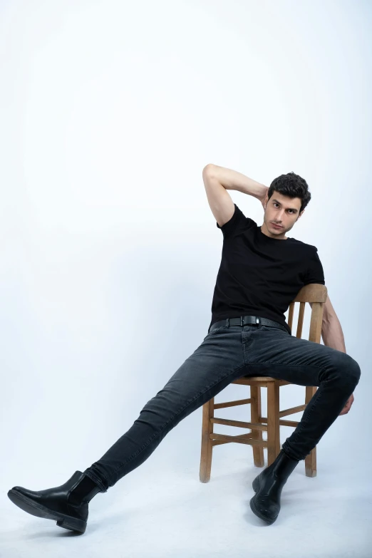 a male posing for a po while sitting down on a wooden chair