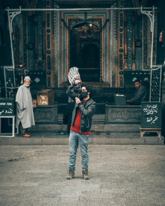 a man stands in front of an ornate building and holds his hand up