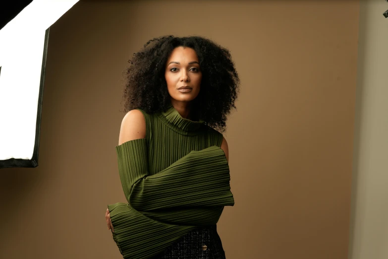 woman standing against a brown background with arms folded