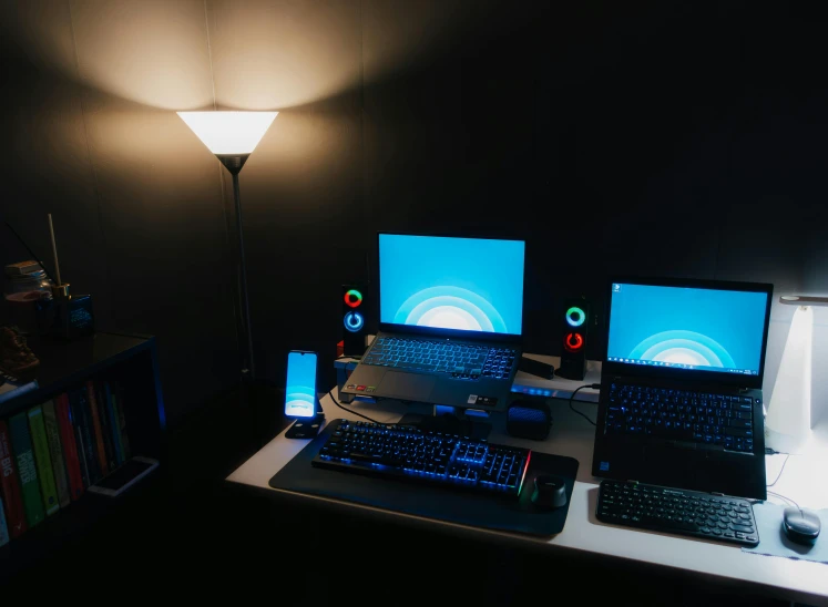 laptop computers are on a table near a lamp