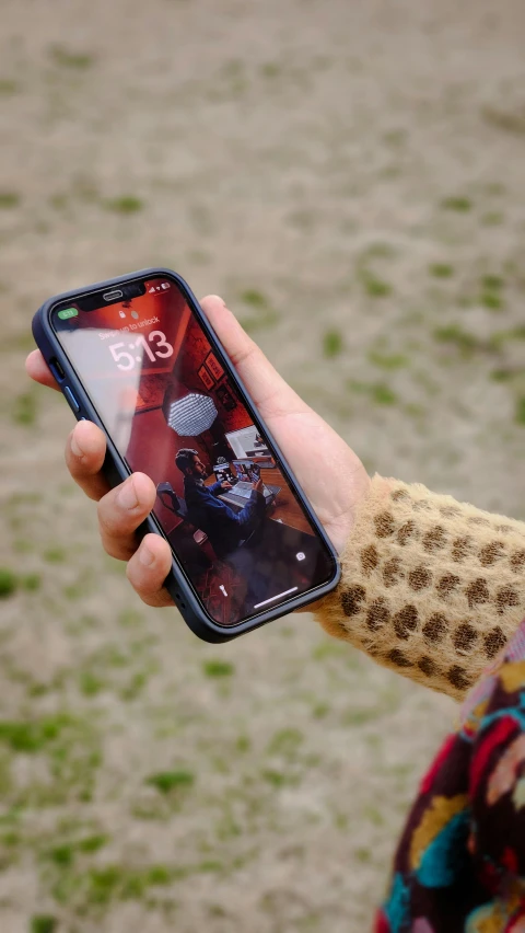 a man holds his cell phone up in a field