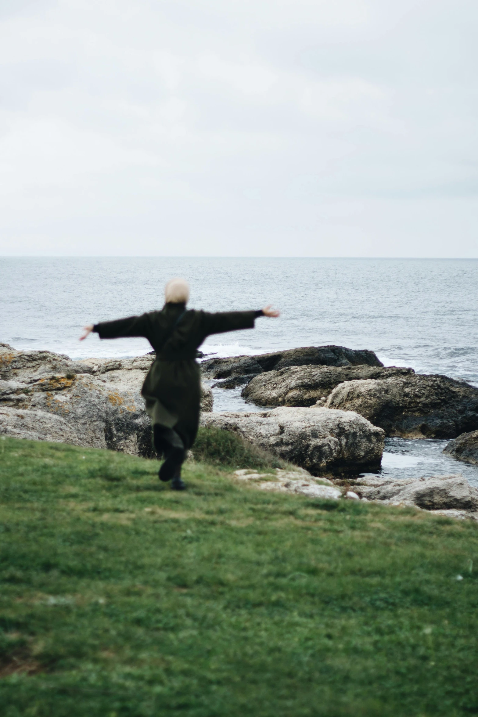 a man that is standing on a hill near some water