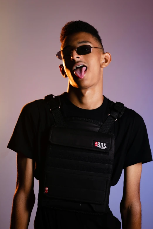 a boy wearing sunglasses and black outfit making a silly face