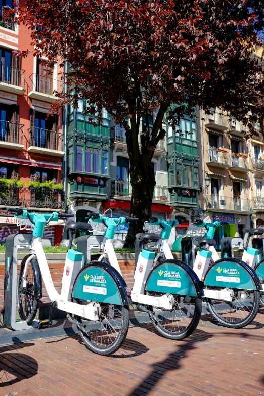 three electric bicycles are parked along the side of a city street