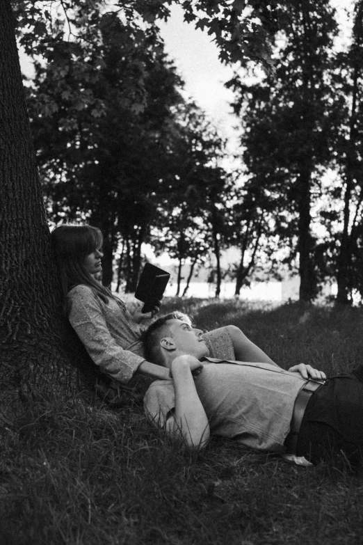 two people sitting next to a tree on the ground