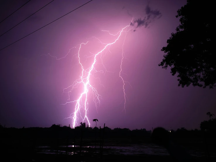 some purple and white lightning striking over a city