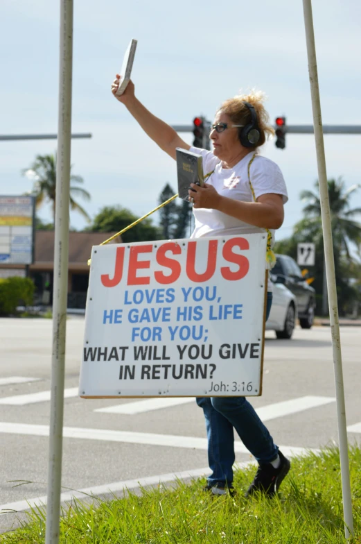 a protester holds up a sign that reads jesus loves you he gave his life for you