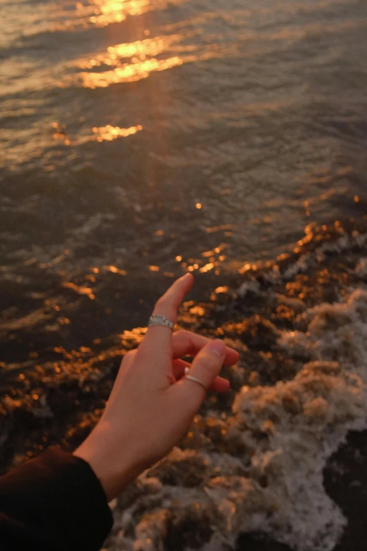 the hand of a person who is pointing down into the water