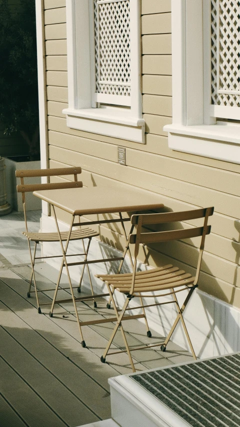 three folding chairs outside of a house with white windows