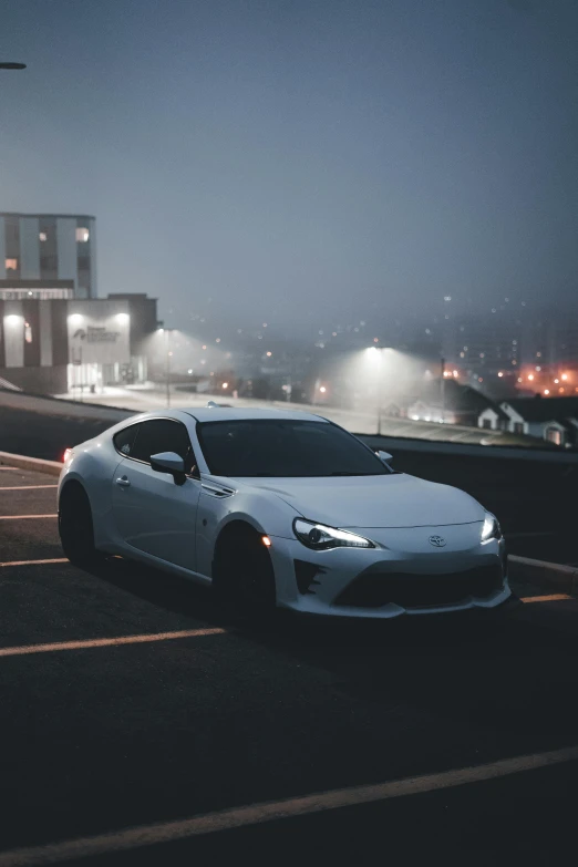 a white car driving down a street in the rain