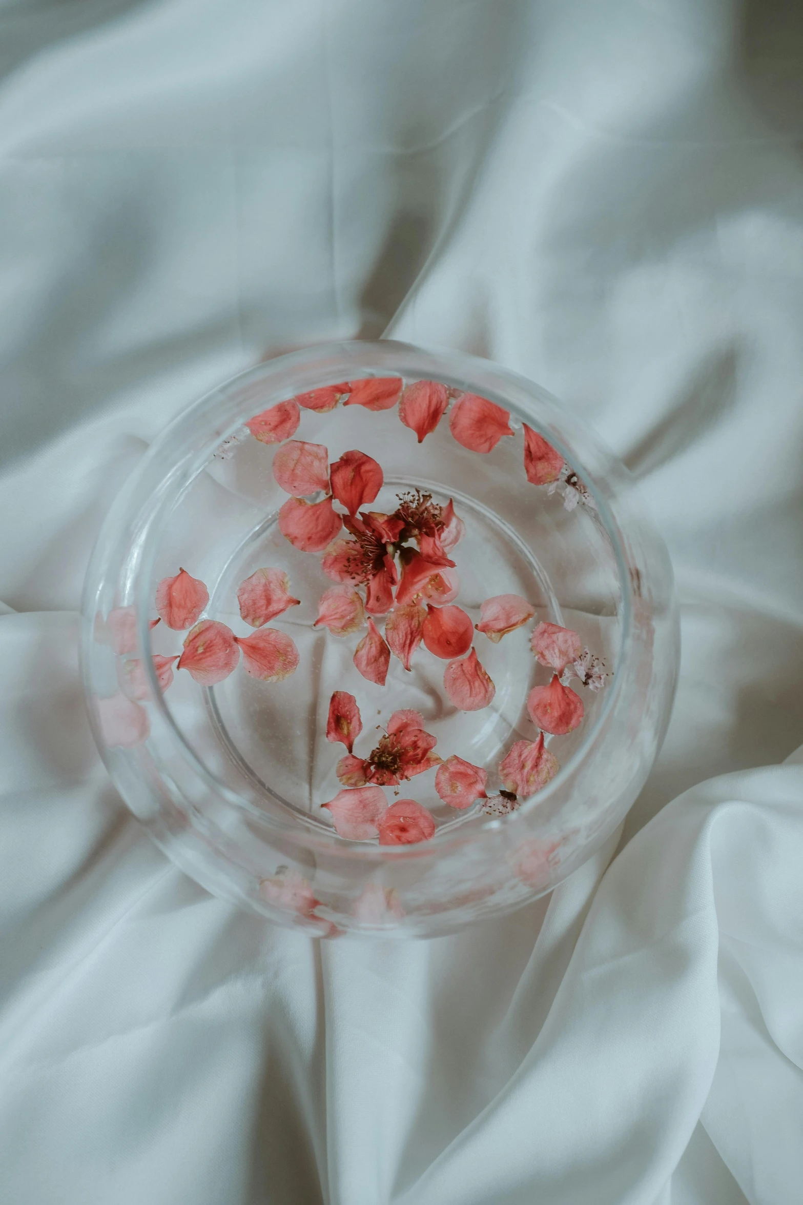 a plastic vase filled with red flowers on top of a bed