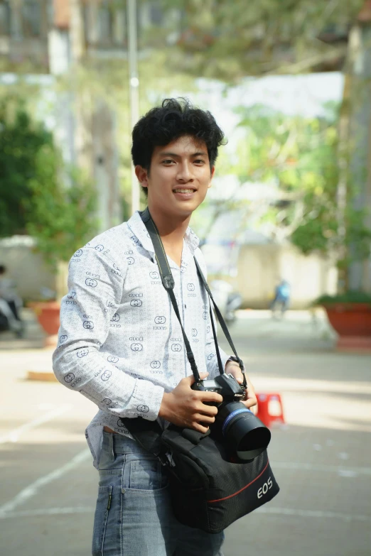 a boy smiles while carrying his camera on his shoulder