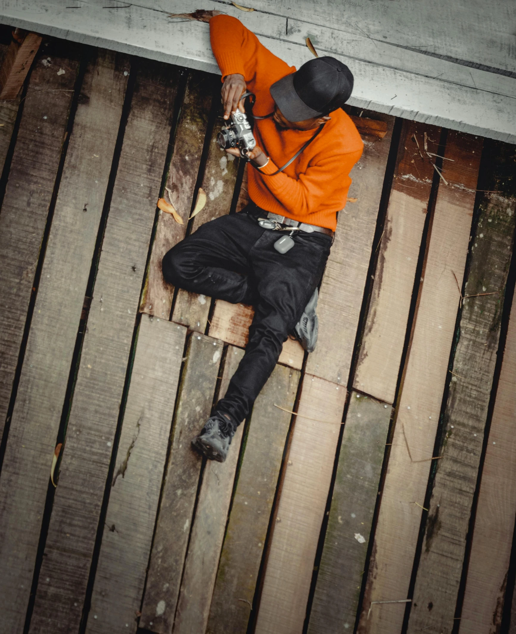 a man wearing a hat and sunglasses is laying on a wooden bench