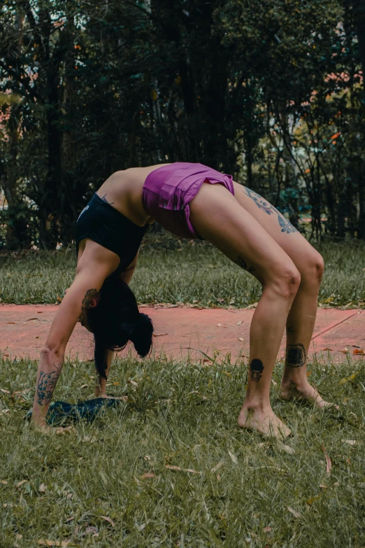 a person doing handstand on the grass in front of trees