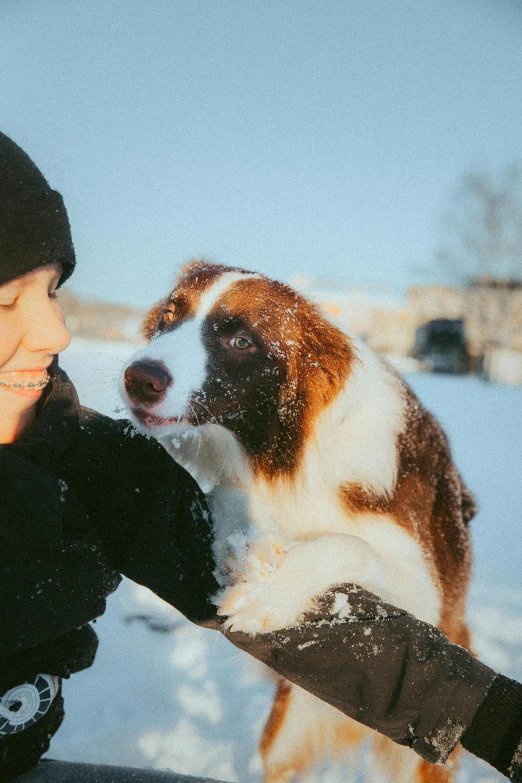 a woman smiles with a brown and white dog