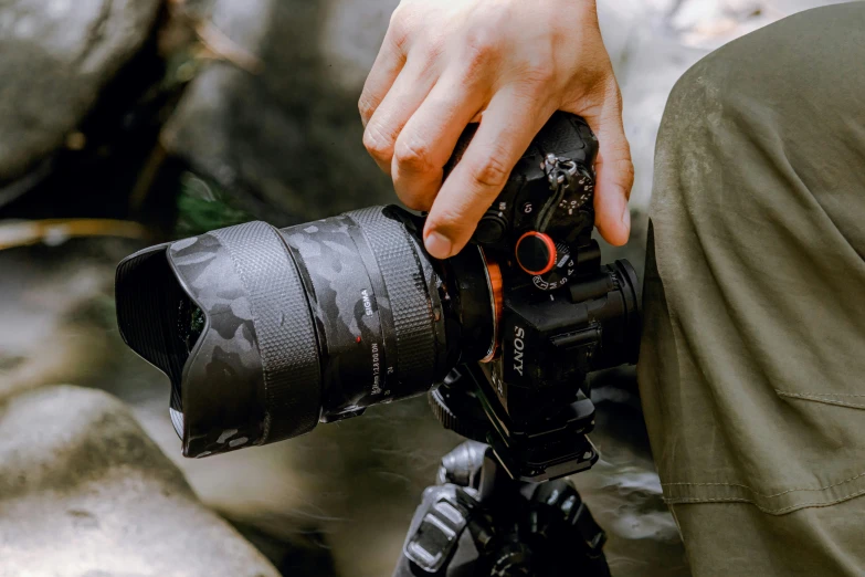 a person is sitting on the rocks and holding his camera