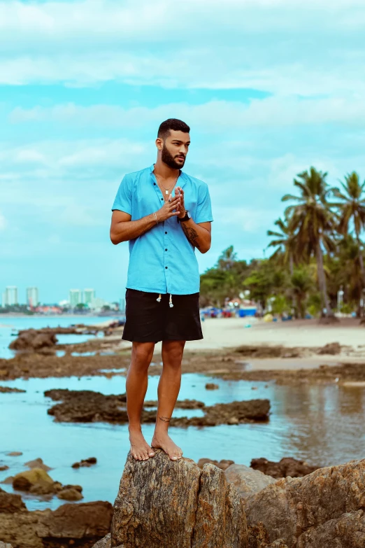 a man standing on a rock holding soing while wearing shorts