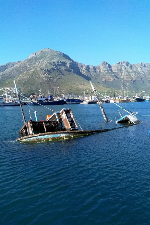 several ships are on the water near a large mountain