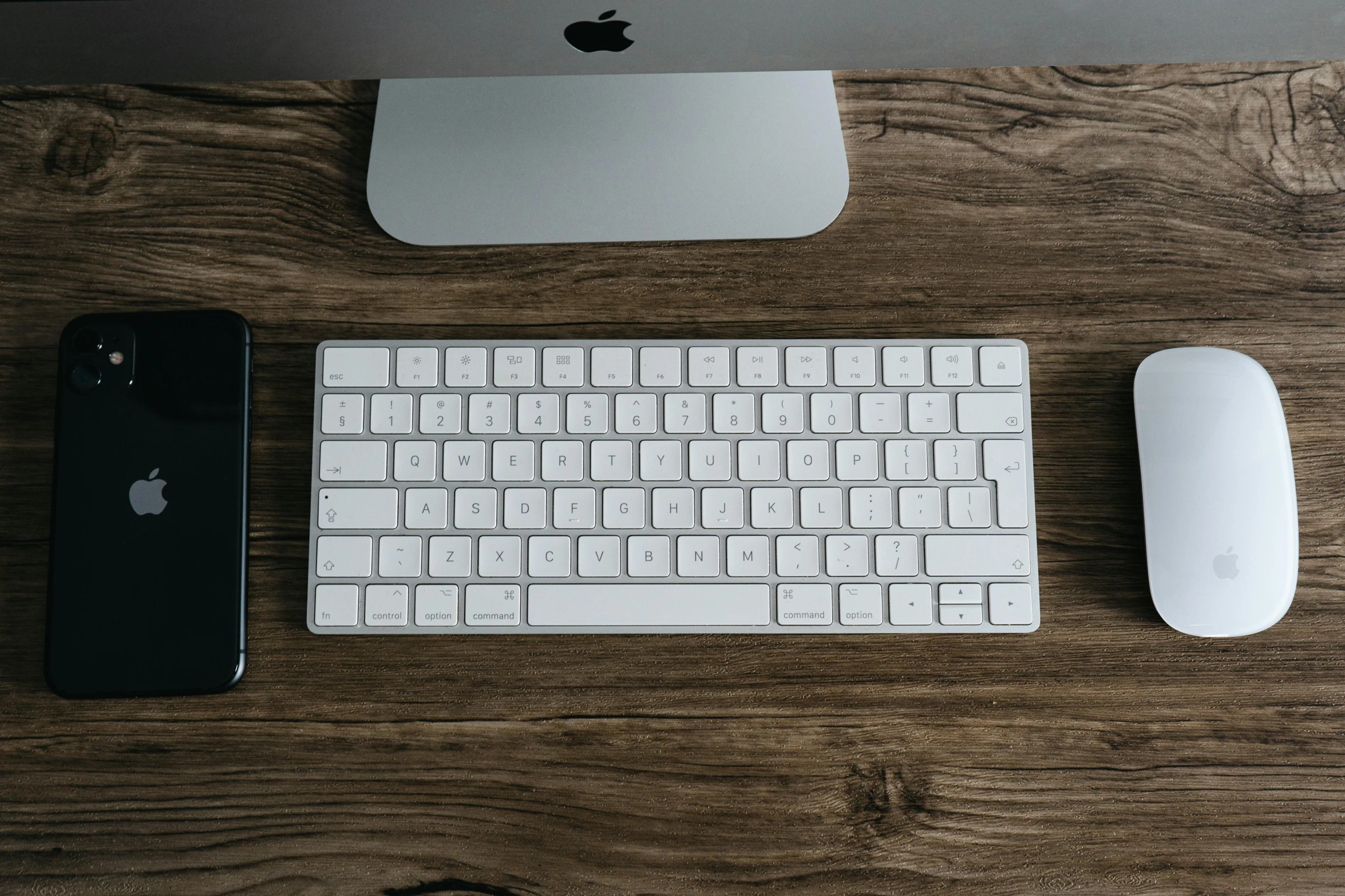 an apple keyboard and mouse on a wooden desk