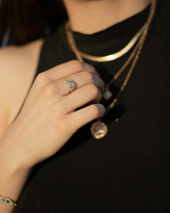 a woman wearing a black top holding onto a necklace with two rings