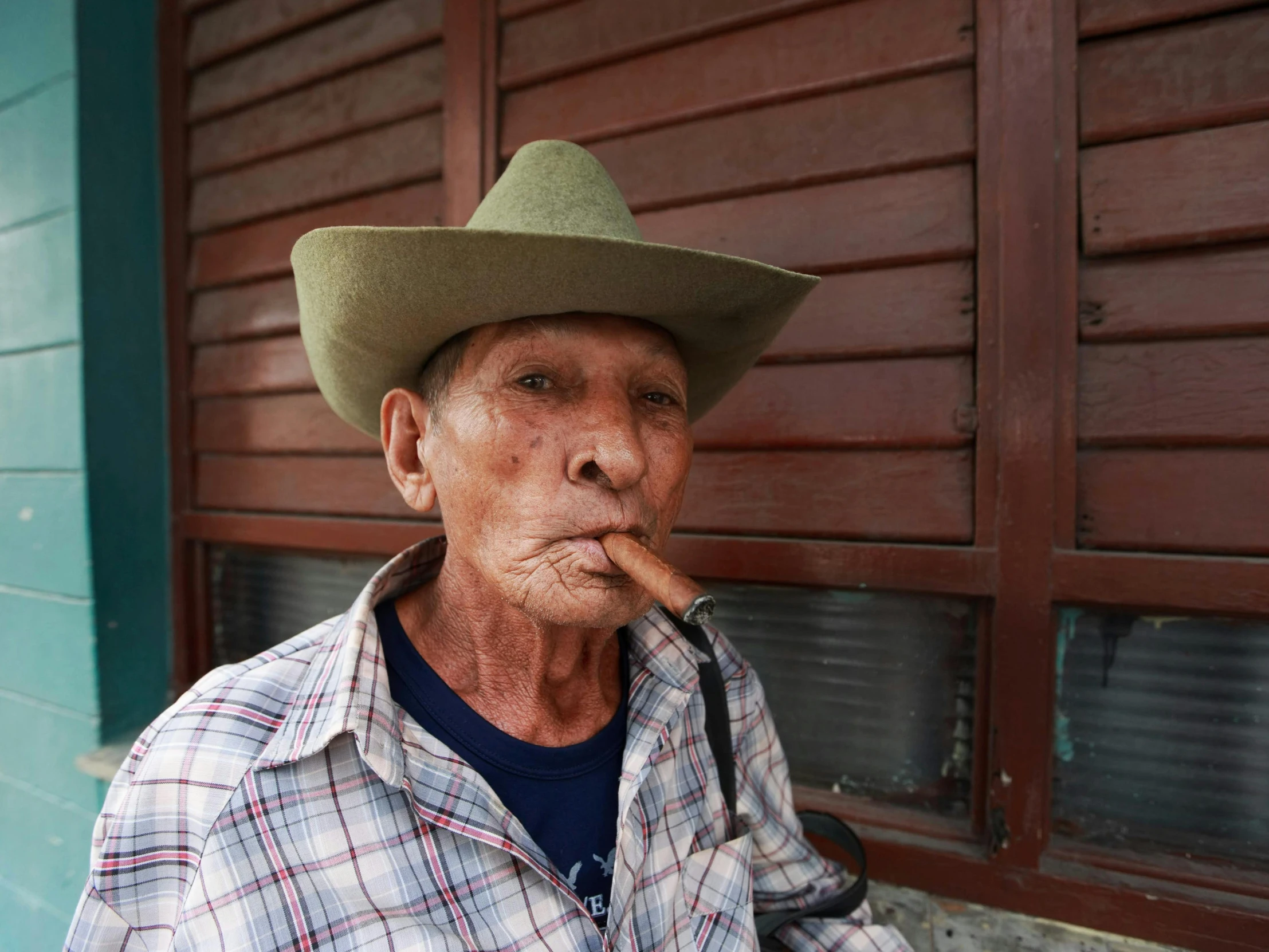 an old man in a cowboy hat and shirt smoking a cigar