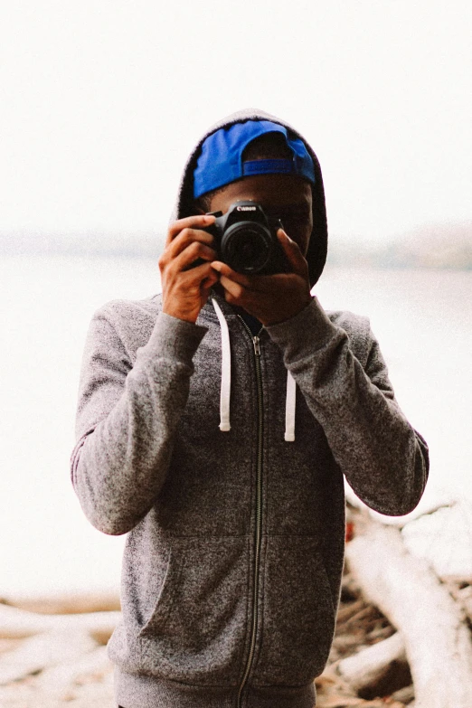 a person wearing a hat taking a picture with a camera