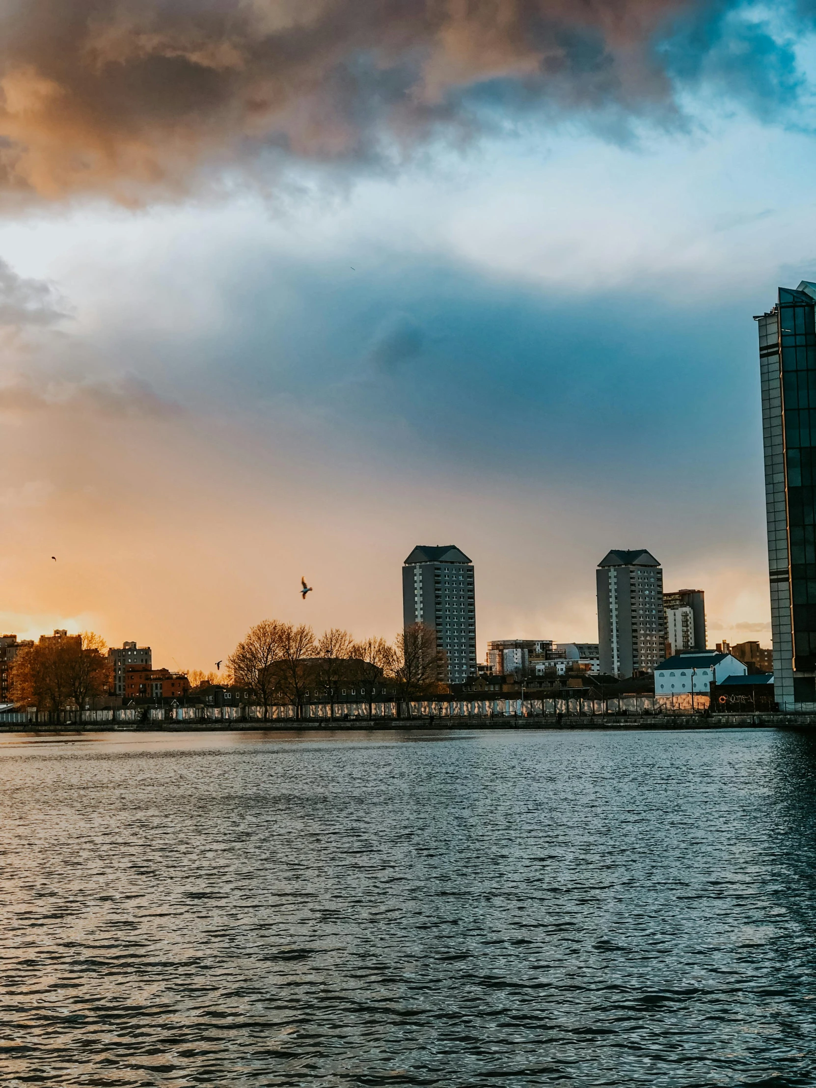 a city skyline with the sun coming down over water