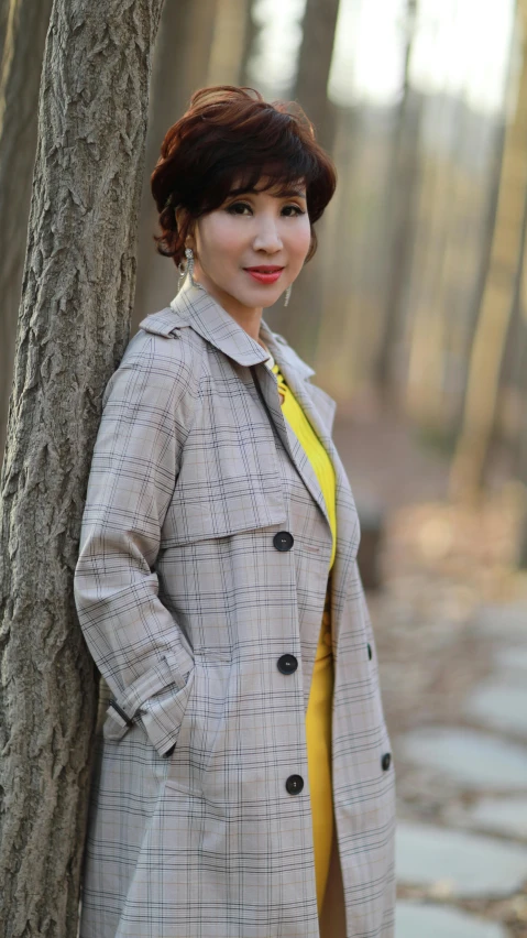 a woman leaning against a tree in the woods