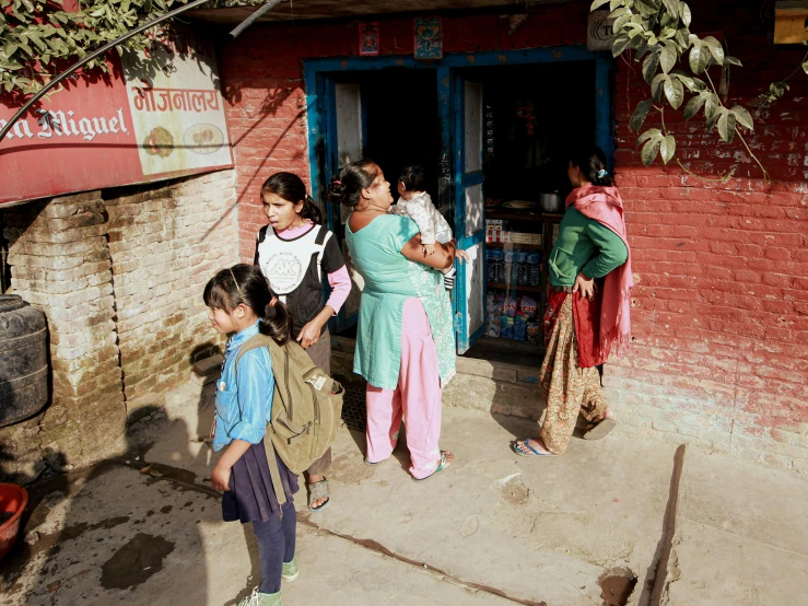 people gather outside of a small, brick building