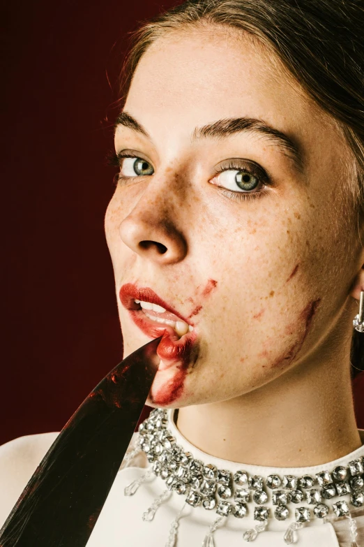 a woman holding a knife to her lip in front of her face