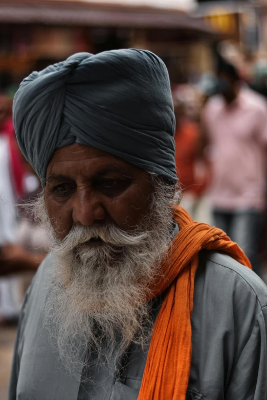 an indian man with a long white beard in an orange wrap