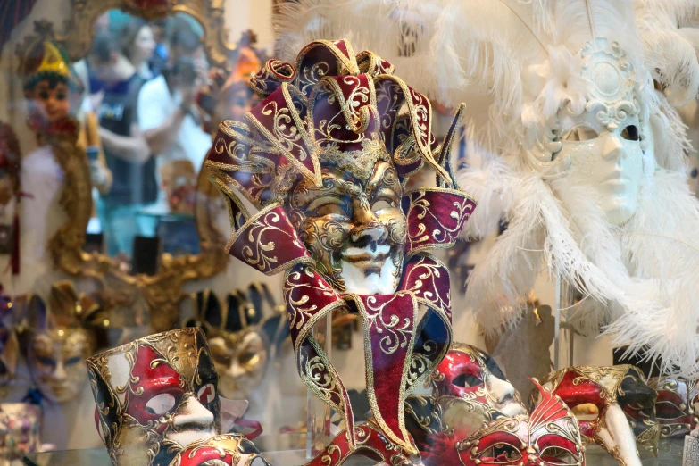 colorful carnival masks sit in front of other costumed items