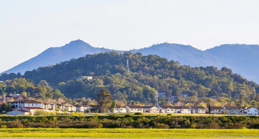 a house sitting in front of a mountain and houses