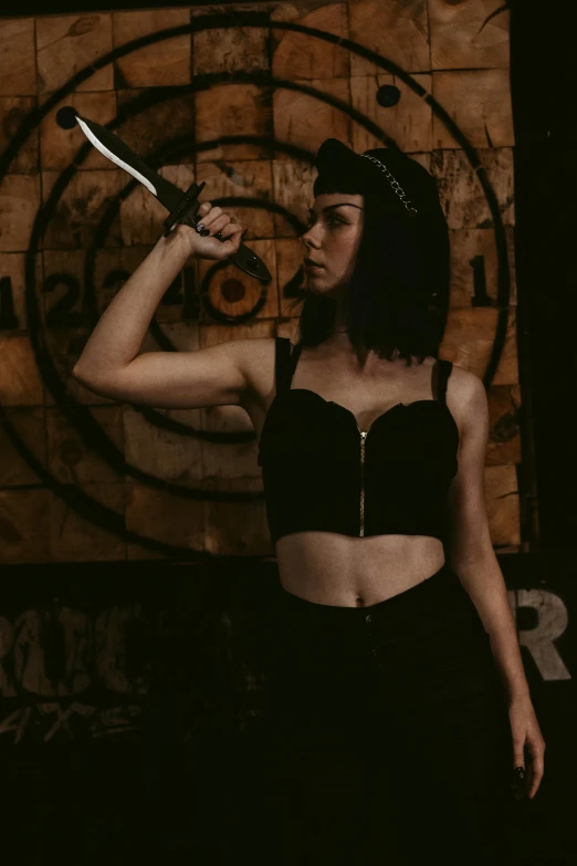 a woman in black top holding a knife near her face