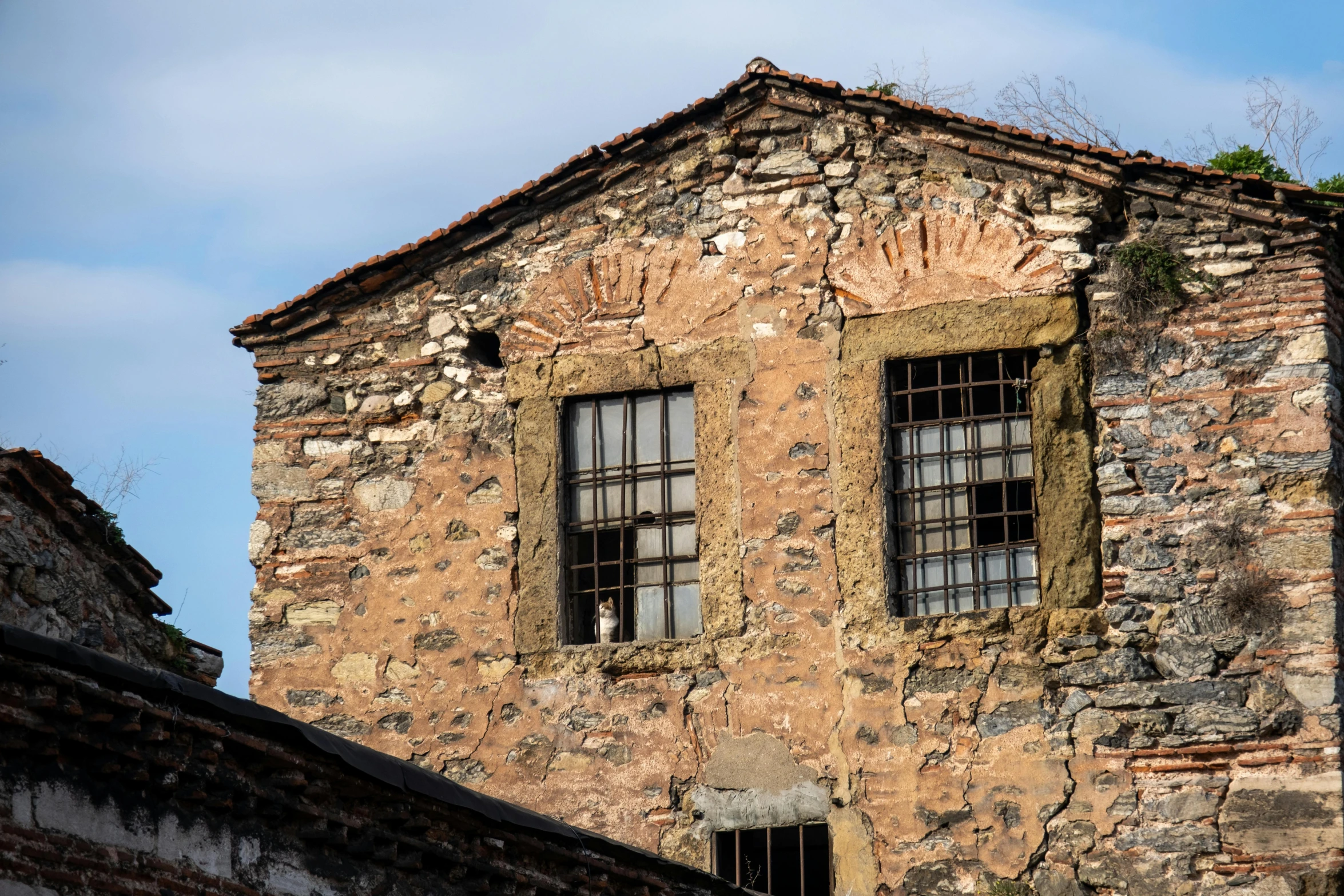 an old brick building with three windows and two small bars on the roof