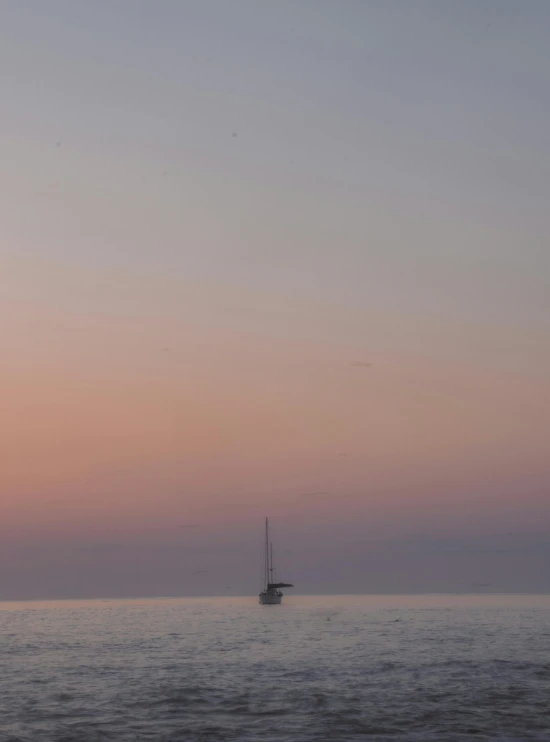 the small sailboat is sailing at sunset on the ocean