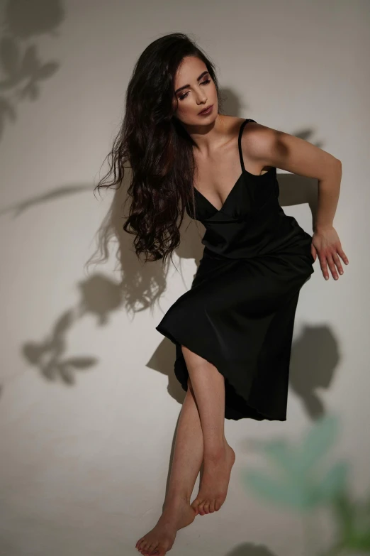 a woman poses against a wall in black dress