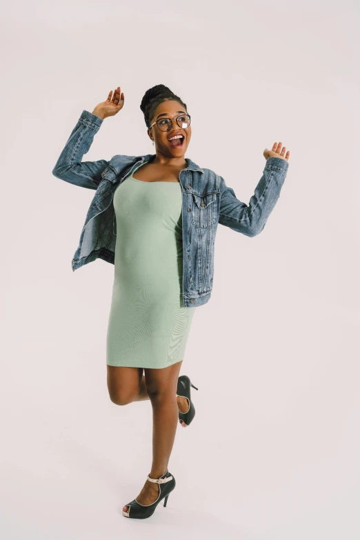 a smiling woman wearing a light green dress and jean jacket