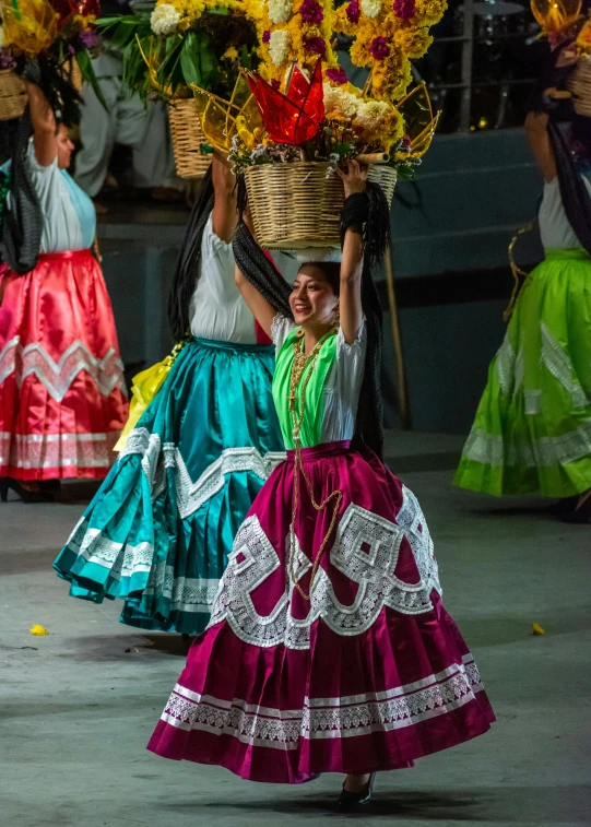 a colorfully dressed mexican woman carrying flowers on her head