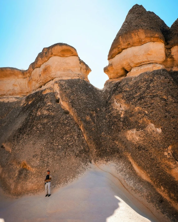 a man stands amongst some large rock formations