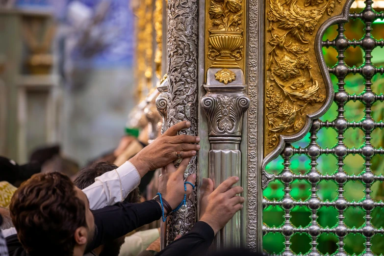 people putting the keys to a gold ornate door