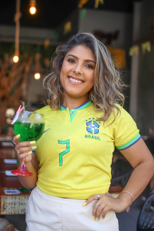 a woman in a soccer jersey holding up a green beverage