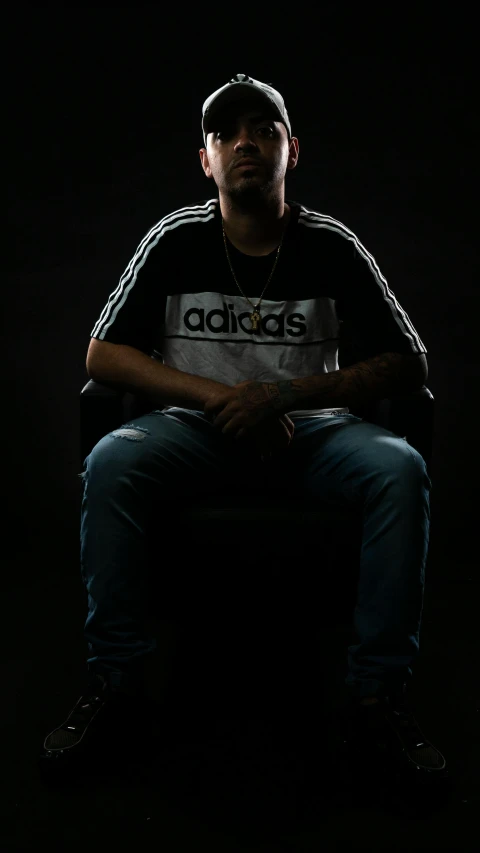 a man sitting down with a black background